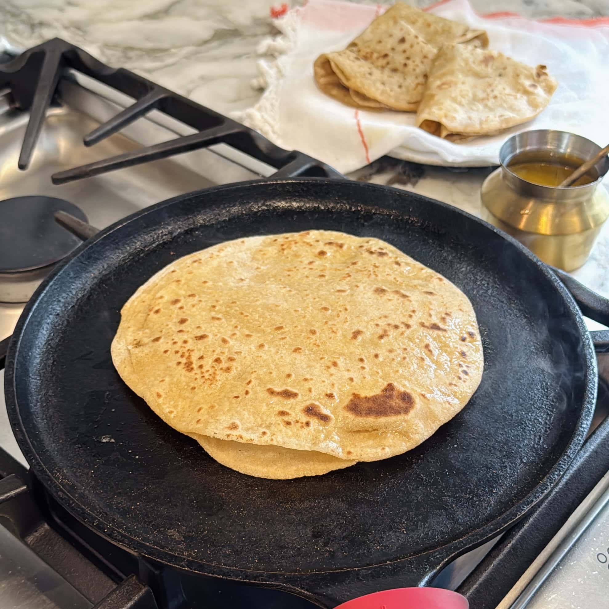 cooked chapati on a cast iron tawa.