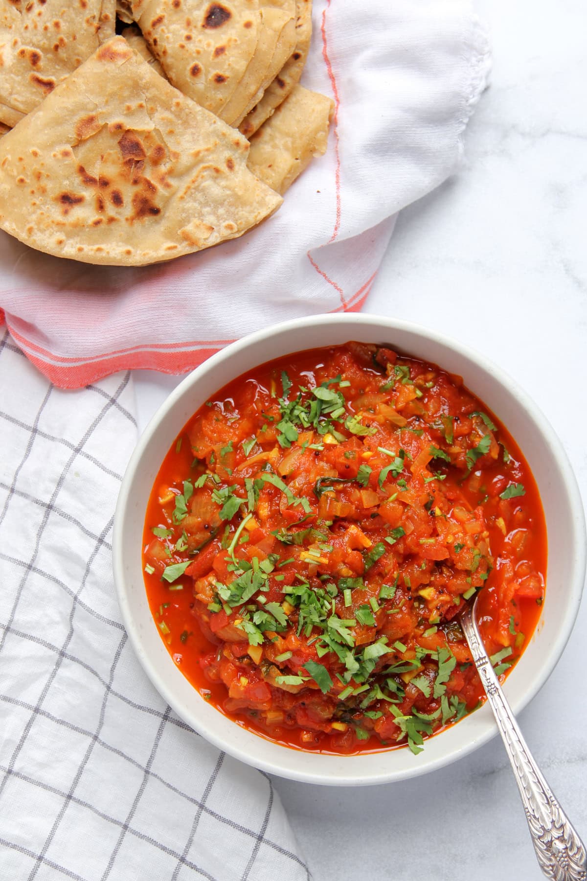 Tomato Chutney in a white bowl served with chapati on the side. 
