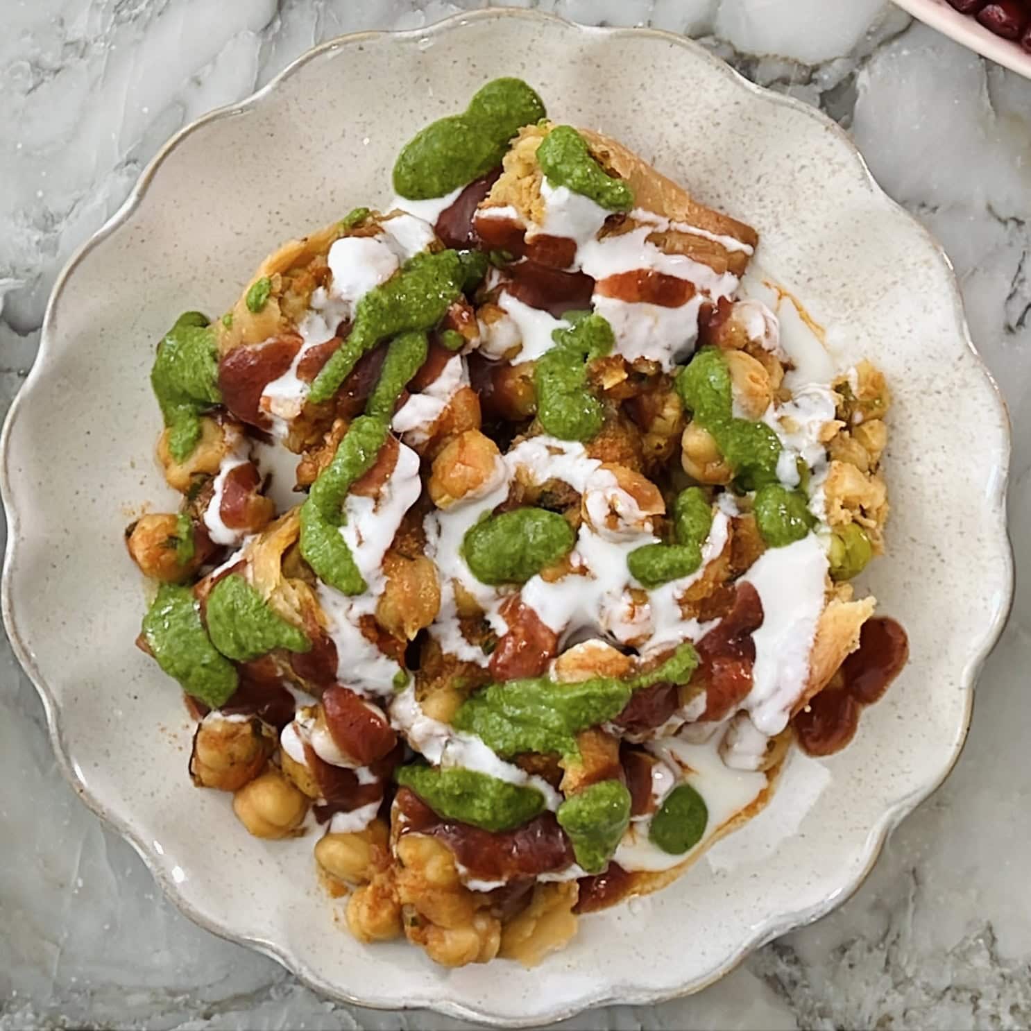 chutneys and yogurt served over samosa and chana masala.