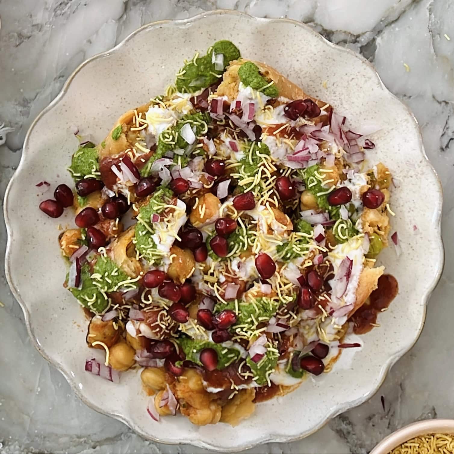 samosa chaat garnished with sev and pomegranate arils.