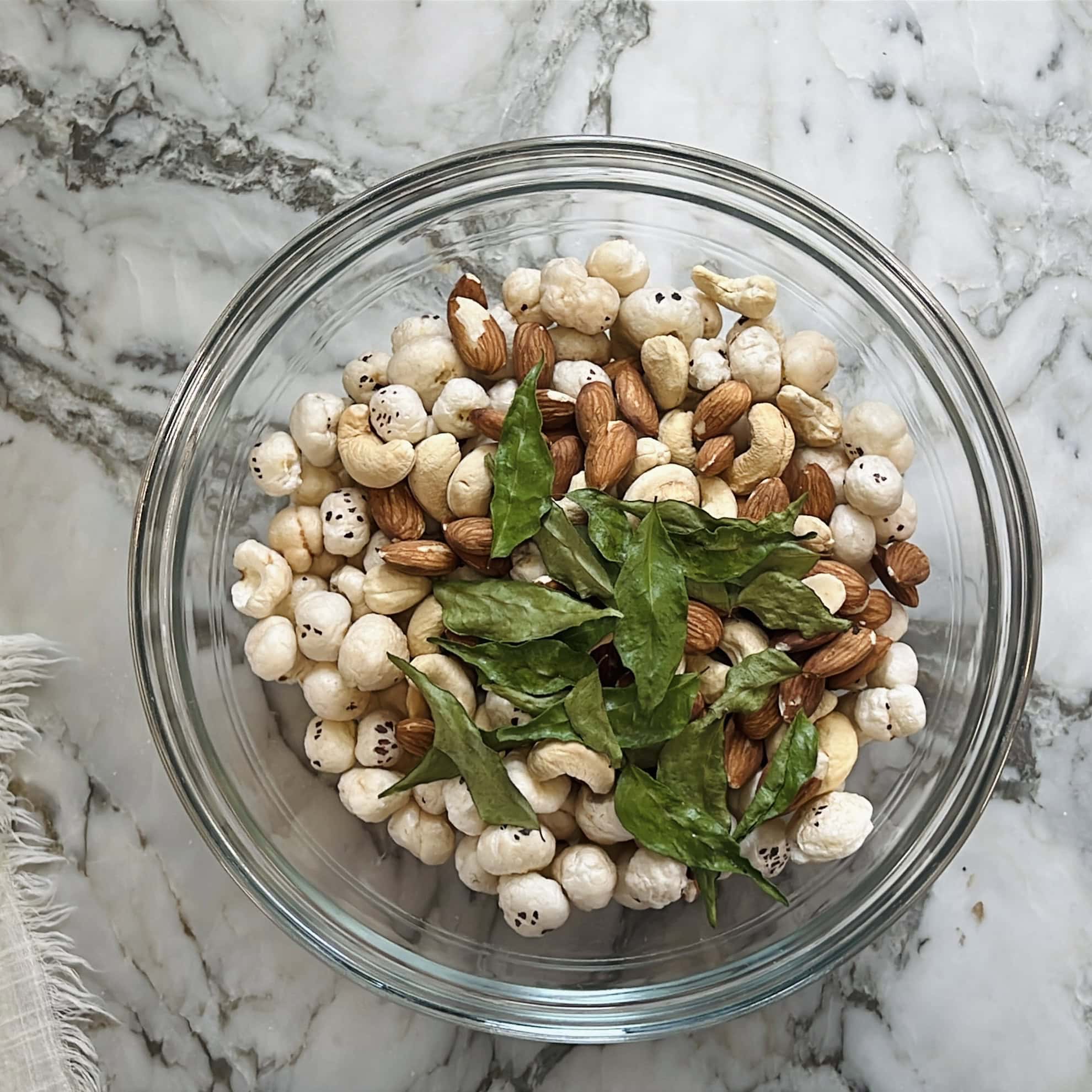 airfried makhana, nuts and curry leaves in a glass jar.