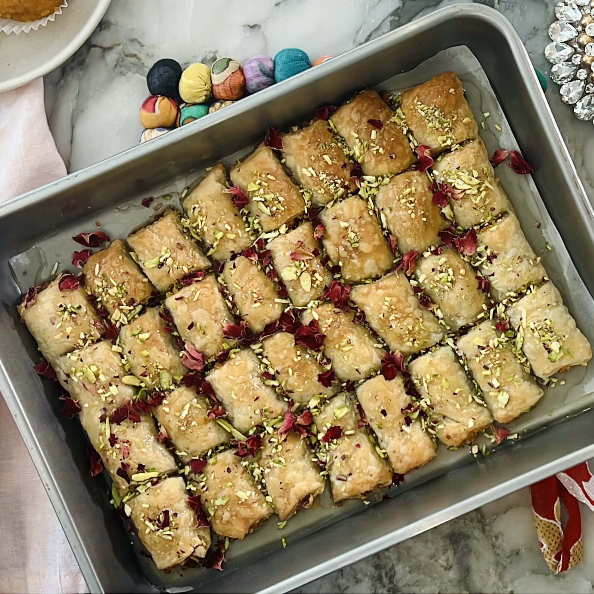 Motichoor pastry mithai bites garnished with pistachios and rose petals.
