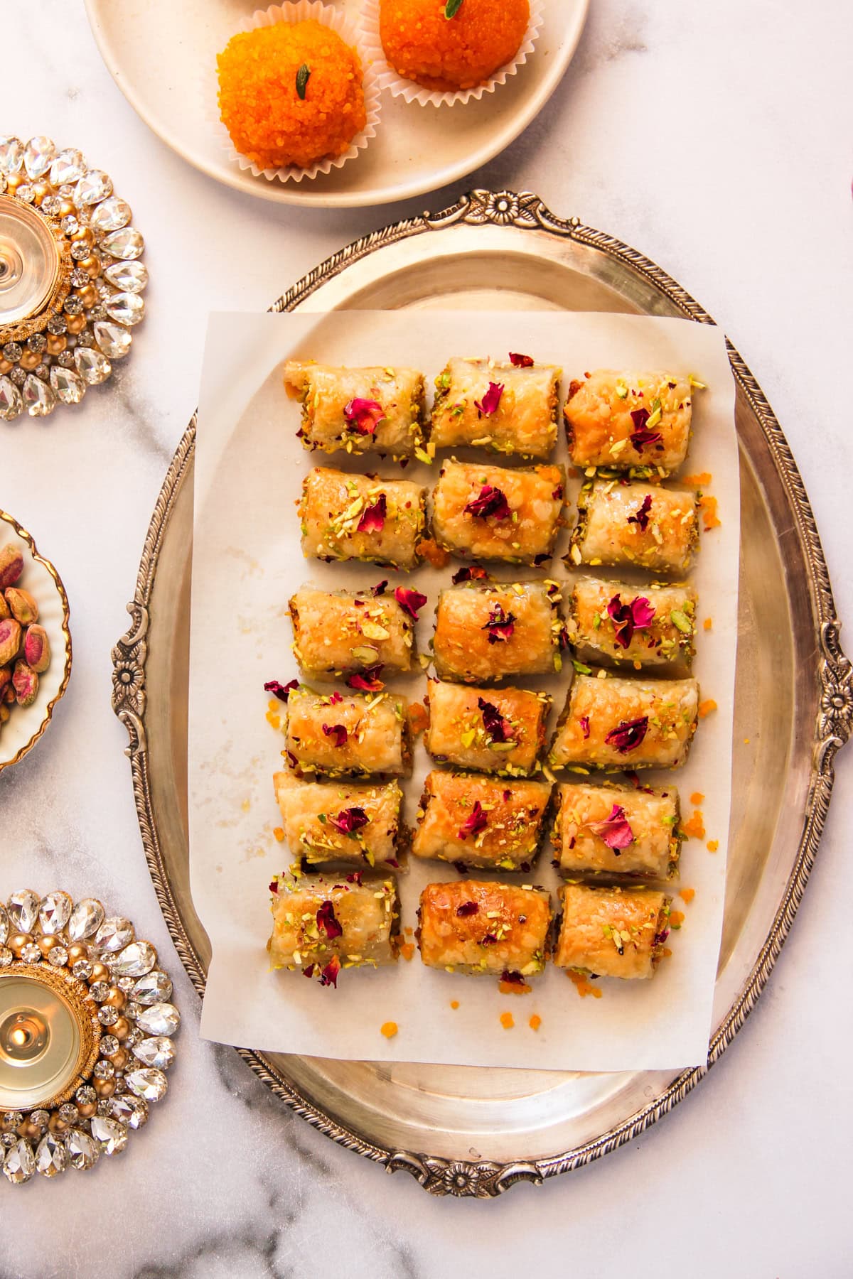 Motichoor pastry mithai bites garnished with pistachios and rose petals.
