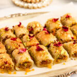 Motichoor pistachio pastry bites garnished with pistachios and dried rose petals in a silver tray