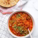Tomato chutney in a white bowl garnished with cilantro.