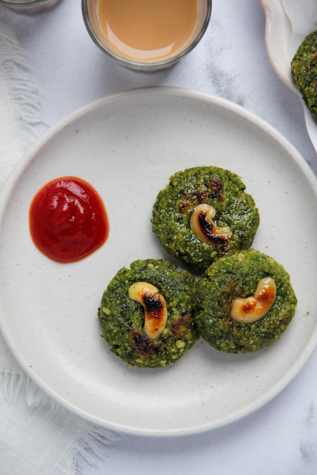 mung bean tikki served with ketchup in a white plate.