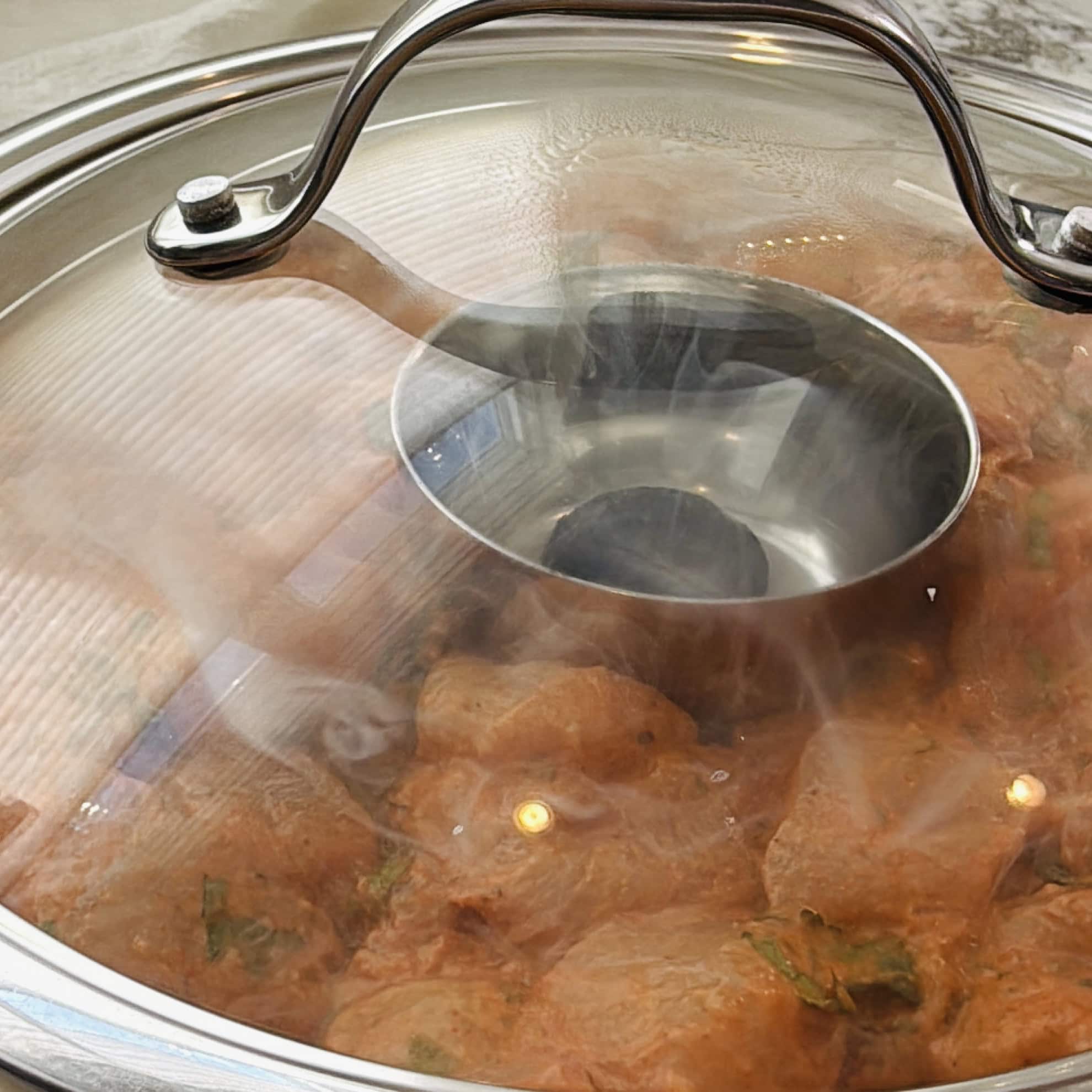 Adding smokey flavors to the marinated chicken using charcoal covered with glass lid.