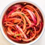 Bowl of Laccha Pyaaz, an Indian onion salad with sliced ​​red onions, tomatoes, herbs and spices, view from above.