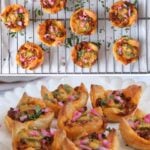 Mini chicken puff pastries topped with chopped onions and herbs, cooling on a rack and arranged on a white plate.