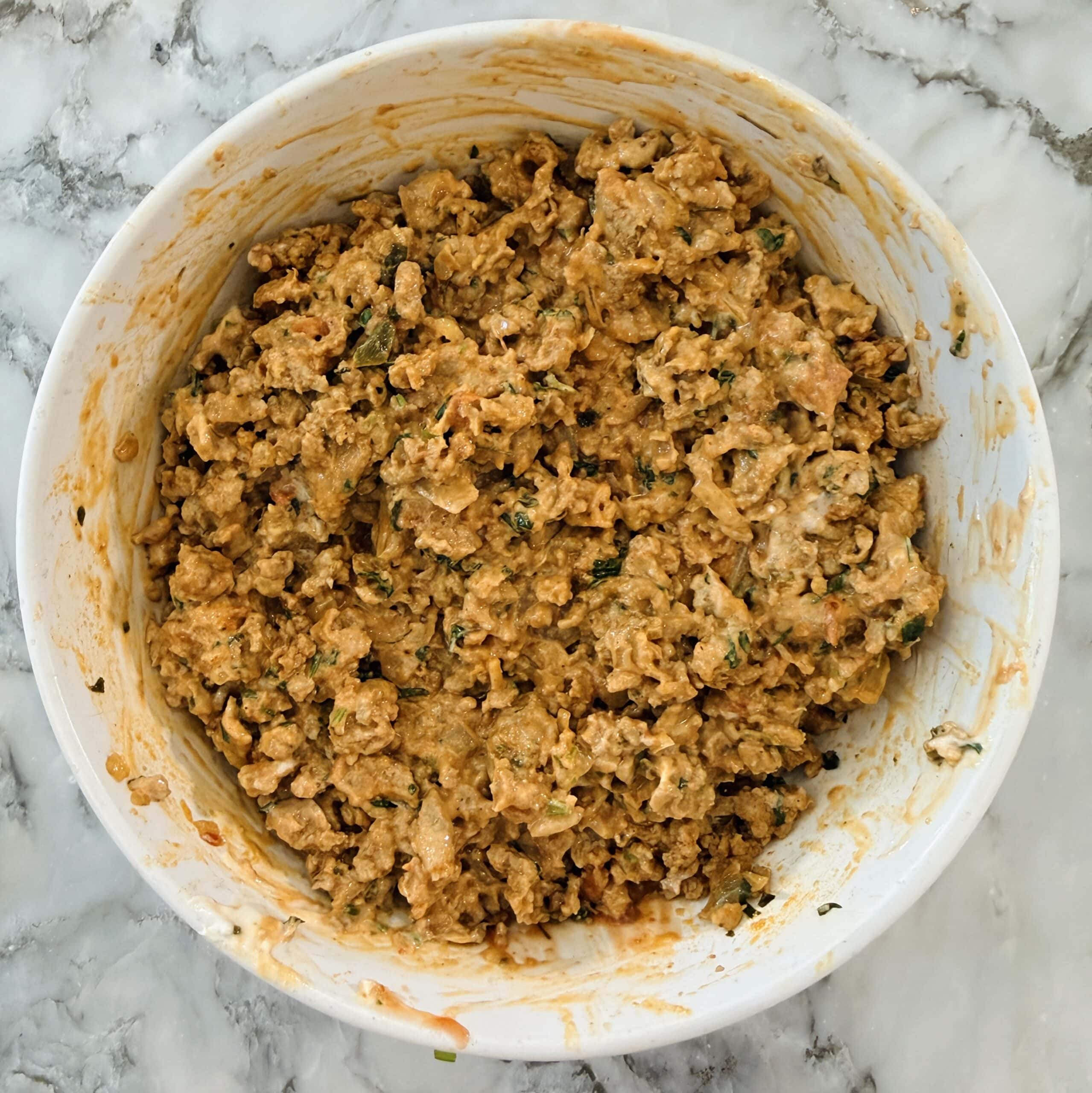 A white bowl filled with kheema mixture, set on a marble countertop.