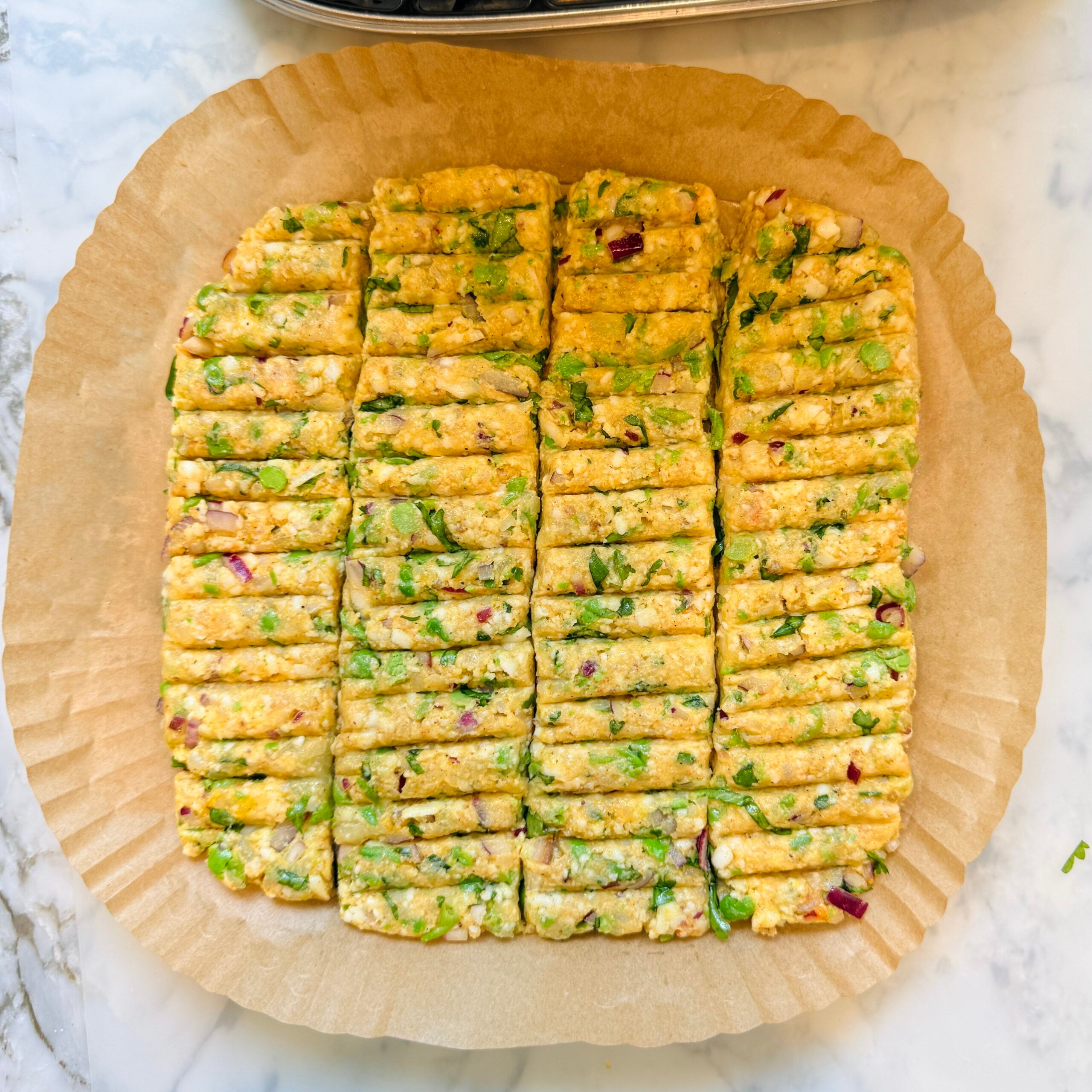 Unbaked rectangular pieces of vegetable kebab mixture arranged neatly on parchment paper liner.