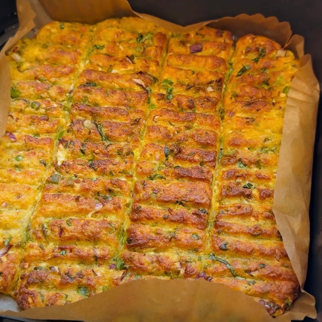 Air fried vegetarian kebabs with golden-brown crust, cut into rectangular sections and lined with parchment paper in a airfryer basket.