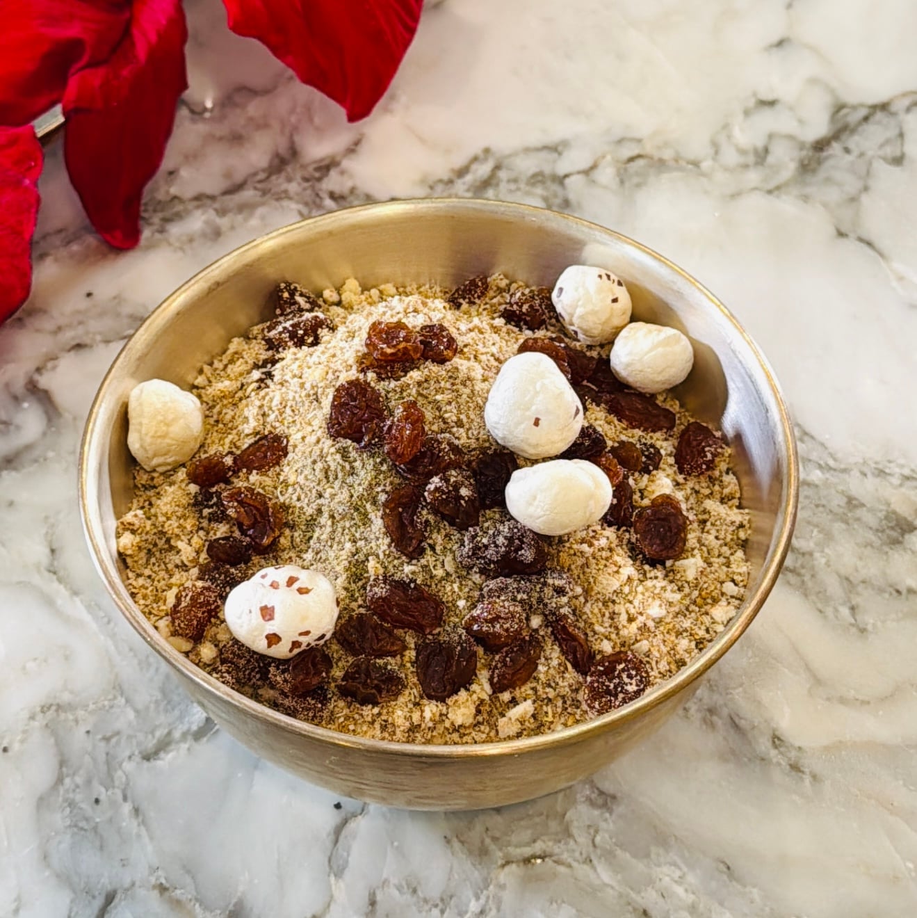 A bowl filled with Panjiri, topped with makhana and raisins.