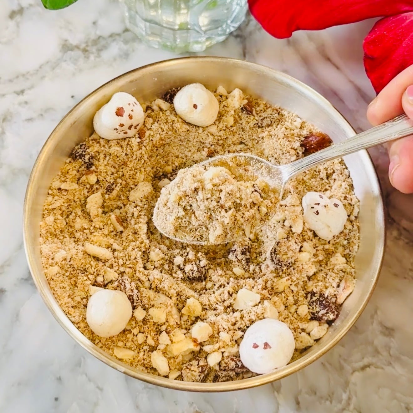 A bowl of panjiri topped with makhana, with a spoon scooping some out.