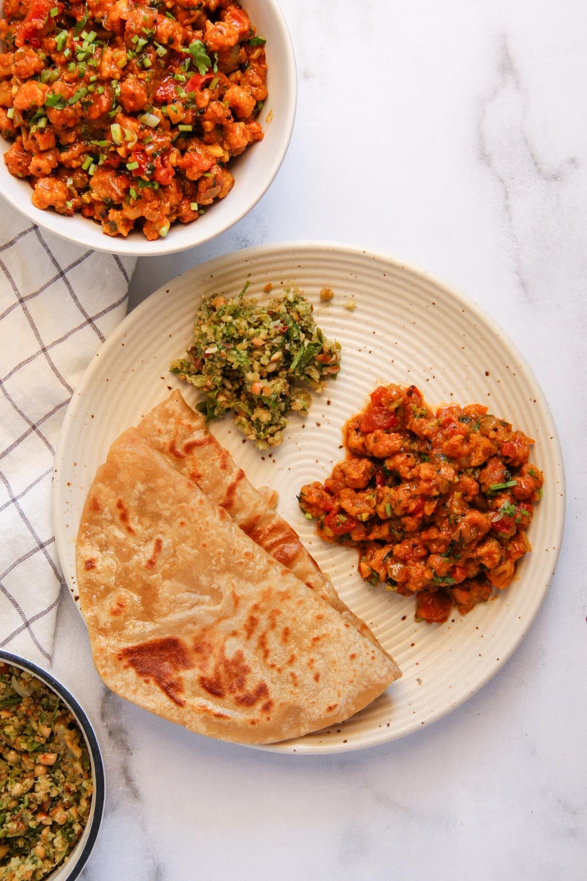 A plate with two pieces chapati, thecha chutney, and sandge bhaji.