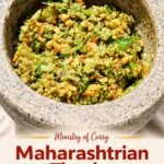 A stone mortar filled with coarse Maharashtrian Thecha, a chutney of crushed green chilies, garlic, and peanuts.