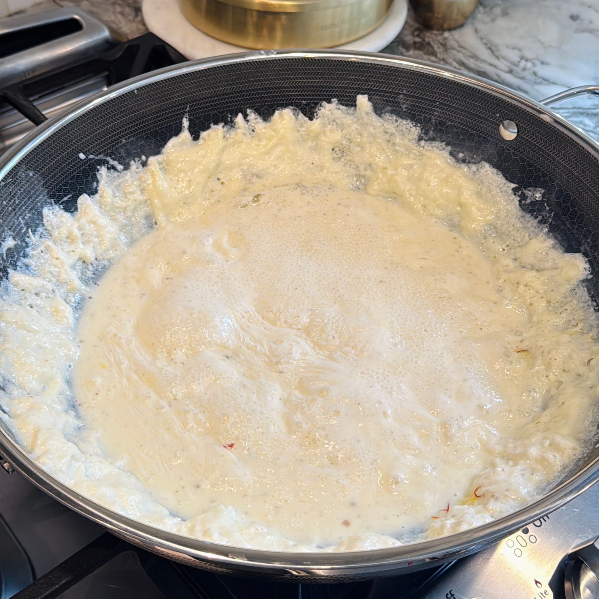 Creamy rabdi simmering in a non-stick frying pan on a stovetop.