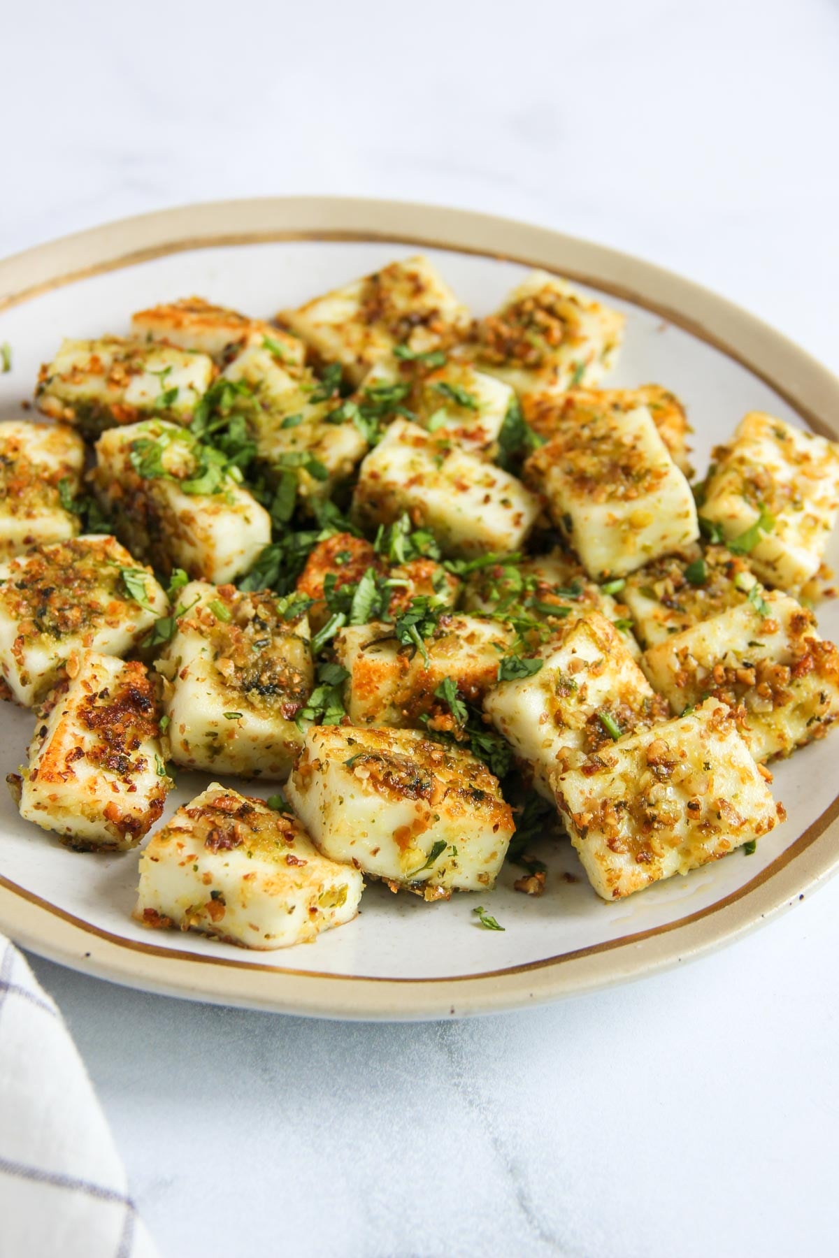 Plate of pan-seared halloumi cubes seasoned with herbs and spices.